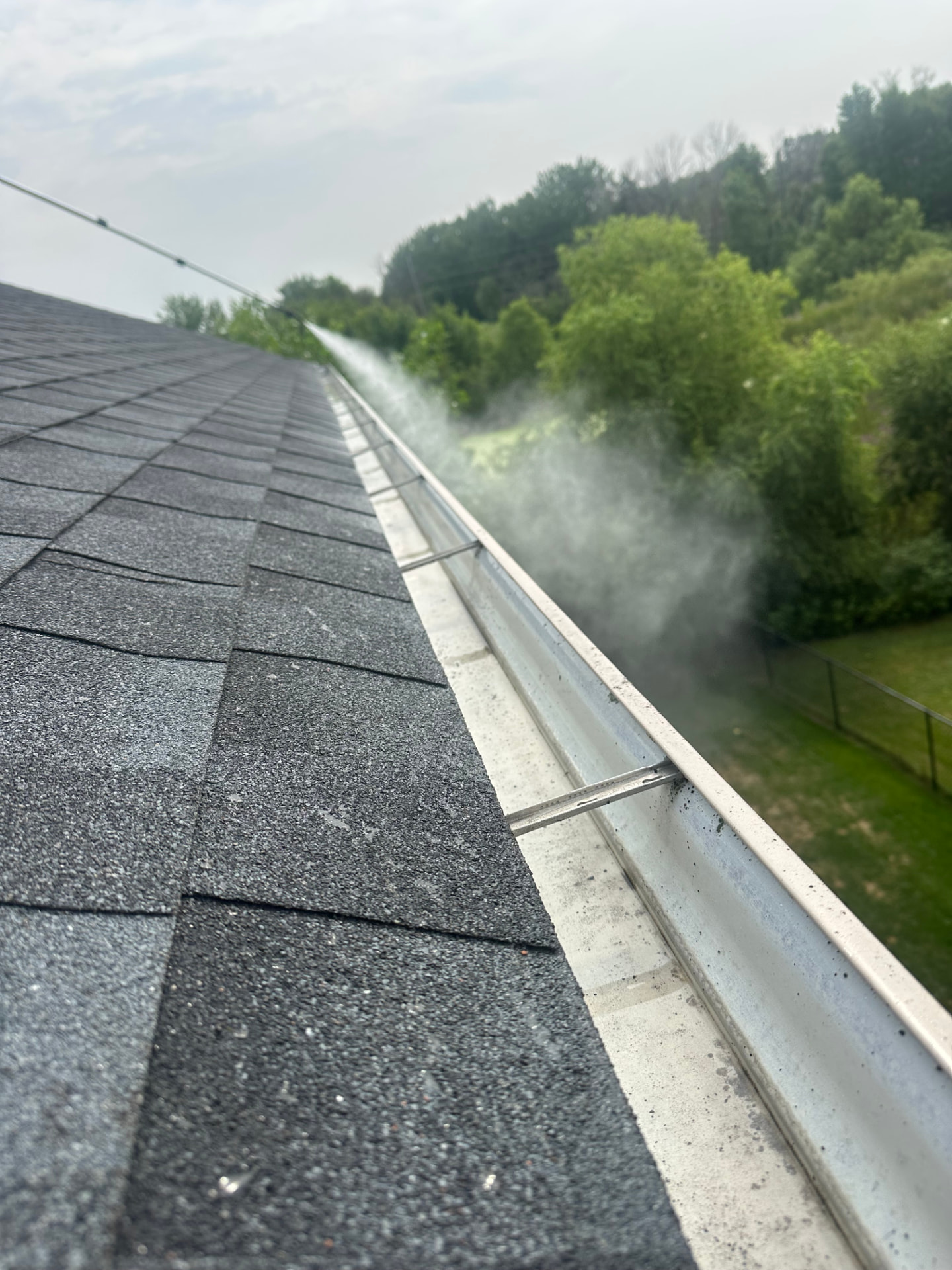 Gutter cleaning in Andover, Minnesota with debris being flushed from the roofline